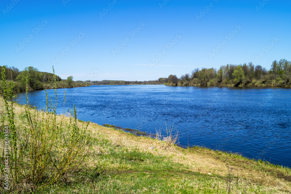 Spring landscape with river on background blue sky