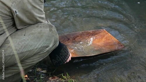 Close up of washing gravel from a gold pan. Gold mining on the river. miner washing gold in the pan. the cold river. autumn. forest. check rocks for gold. The old method of gold mining.