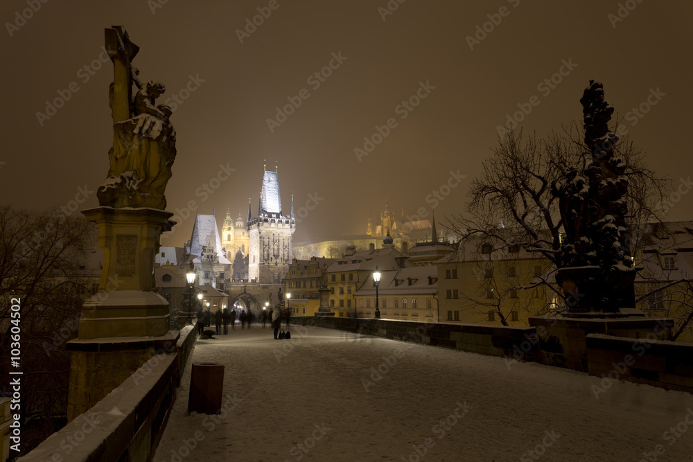 Night snowy Prague gothic Castle, Bridge Tower and St. Nicholas' Cathedral from Charles Bridge with its Statues, Czech republic