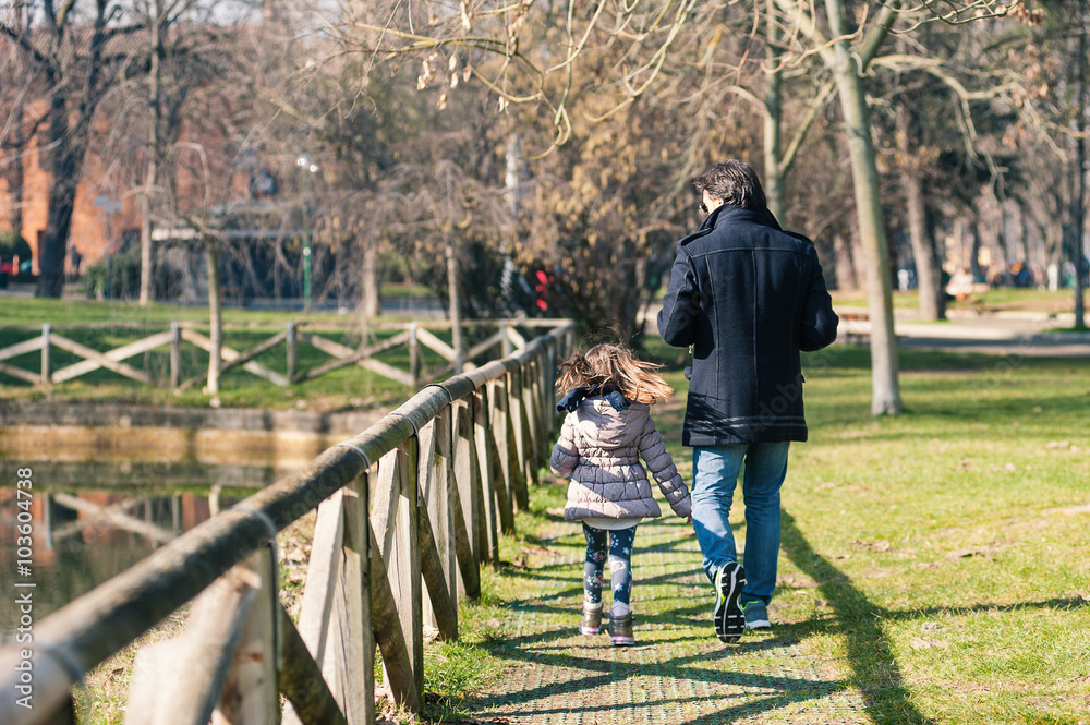 Father and daughter walking in a park.
