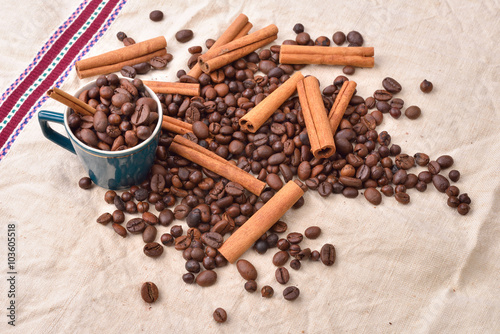 Cup with coffee beans cinnamon stick on jute background. Morning