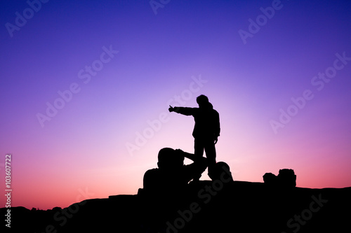 Hiker taking photo on sunset background