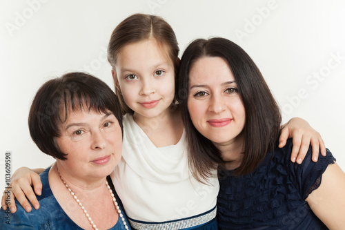 The granddaughter embraces the grandmother and mother