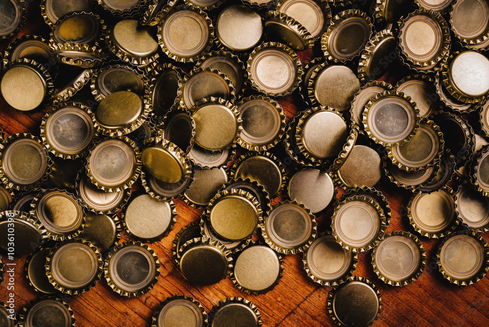 Large pile of beer bottle caps on wooden desk Large pile of beer bottle caps on wooden desk