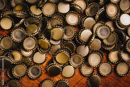 Large pile of beer bottle caps on wooden desk