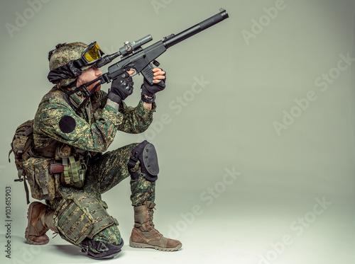 Special forces soldier with rifle on grey background