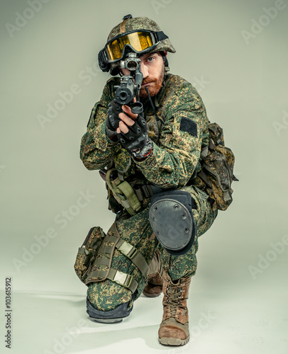 Special forces soldier with rifle on grey background