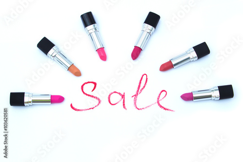 Word "sale", written with red lipstick, and six different lipsti