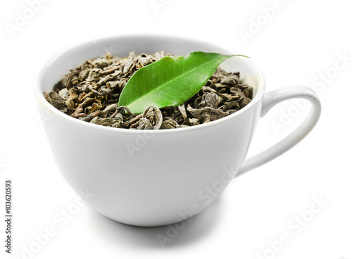 Cup with dry tea and green leaf, isolated on white