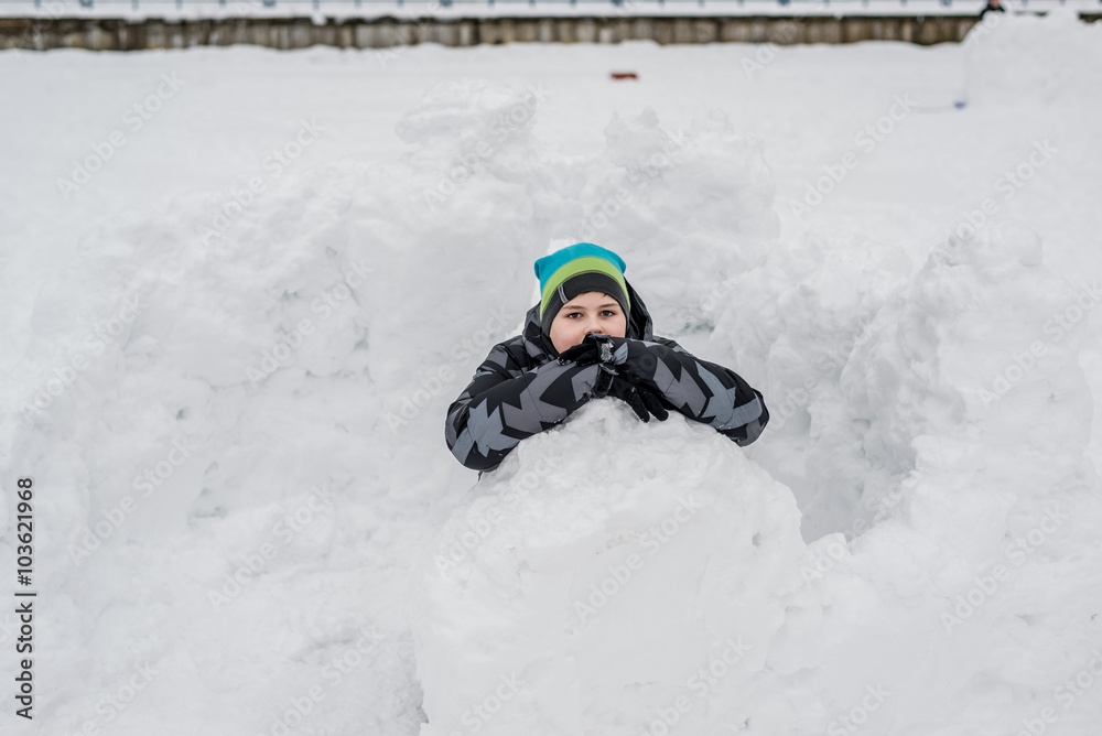 Teen boy sitting in  homemade snow fort