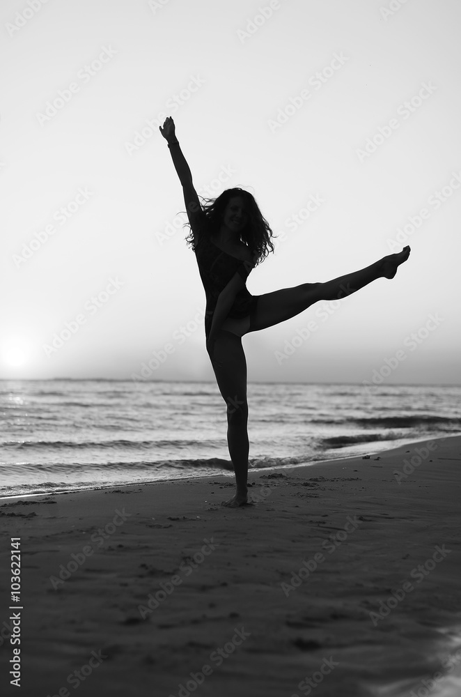 Obraz premium girl doing gymnastics on the beach at sunset