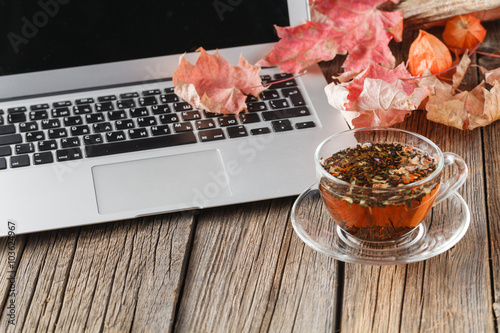 Cup of herbal tea on table with laptop photo