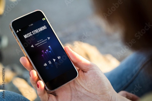 woman sitting in the street holding her smartphone with music on