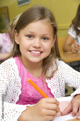 Schoolgirl in a classroom is looking to camera.