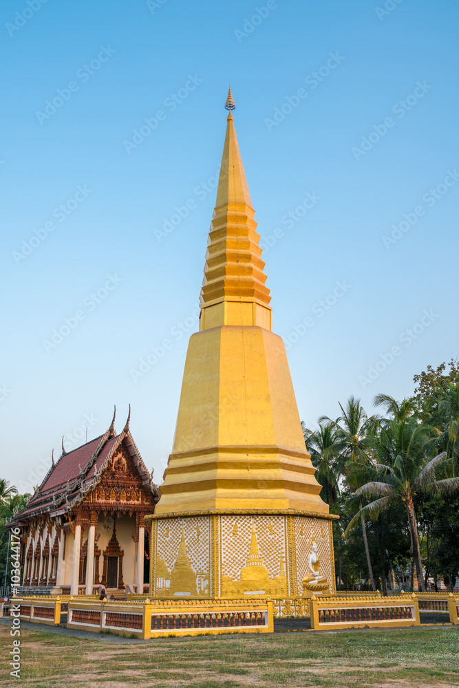 Naklejka premium Golden pagoda with Old Buddhism church (Ubosot) in public temple, Thailand