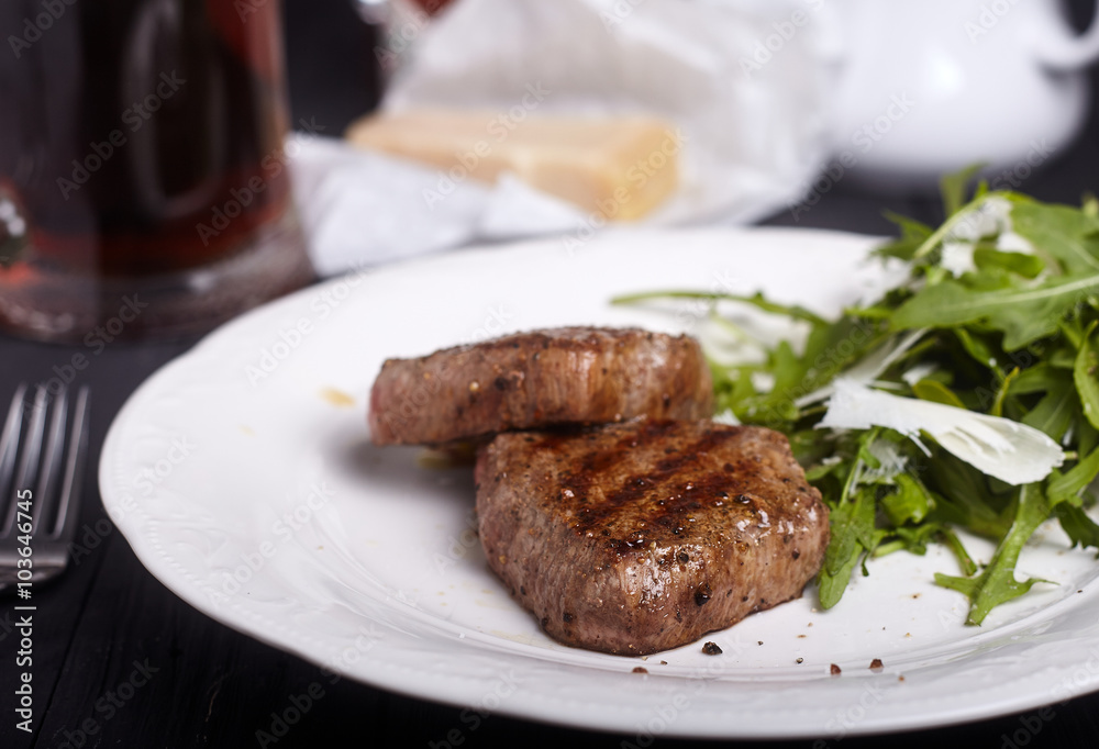 Steak with arugula salad on dark background