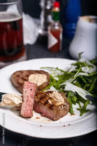 Steak with arugula salad on dark background