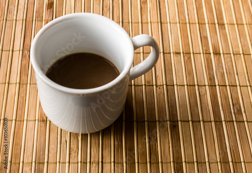 Coffee cup on a bamboo pad