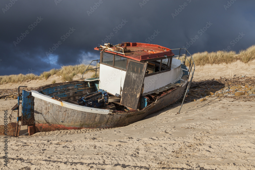 Abandoned and wrecked old fishing boat at the mouth of River Wansbeck, on the coast of Northumberland, England, UK. Abandoned and wrecked old fishing boat at the mouth of River Wansbeck, on the coast of Northumberland, England, UK.