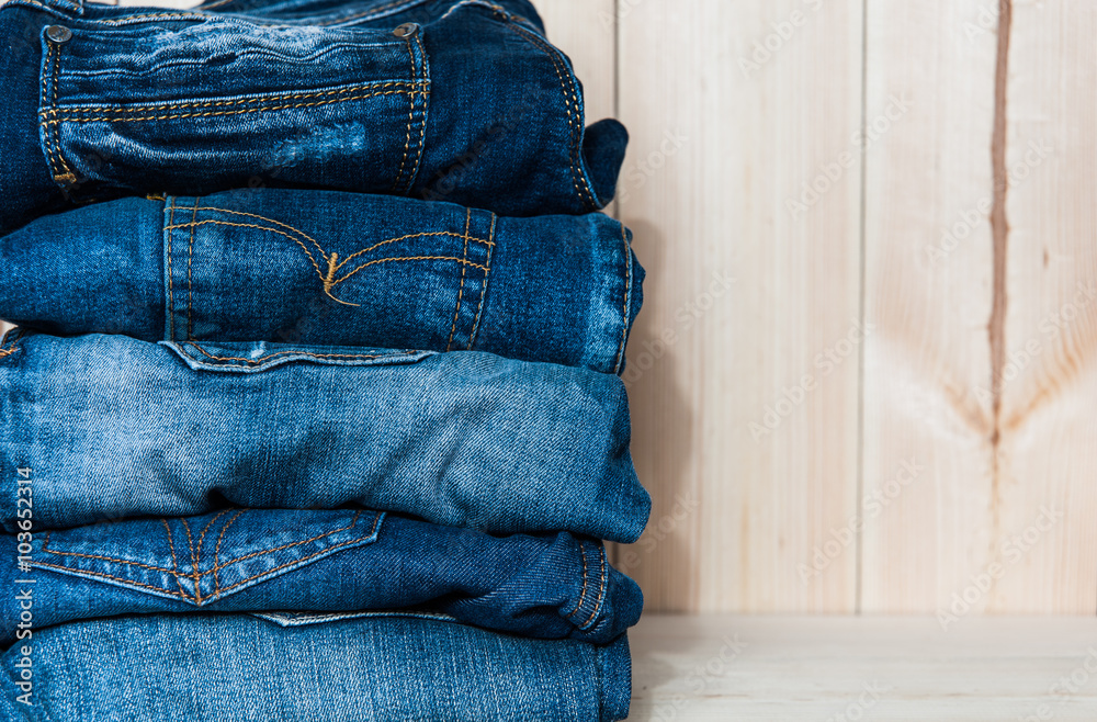 Fashionable clothes. pile of jeans on a wooden background Fashionable clothes. pile of jeans on a wooden background