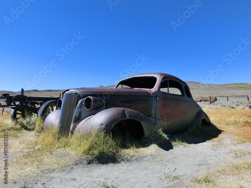 Abandoned rusty metal car in desert sun - landscape color photo