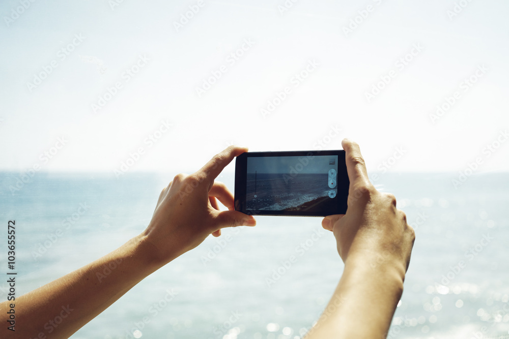 Detail view of a young woman hands holding a smartphone device up and taking photos