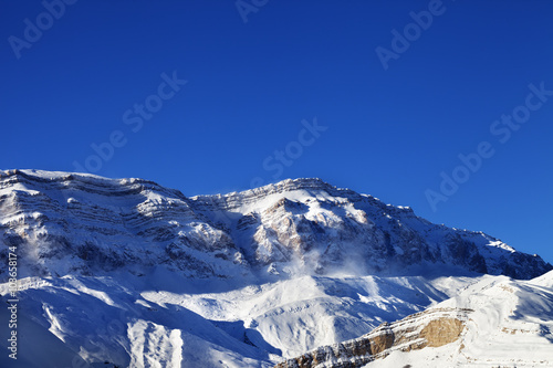 Snowy mountains at sun windy day