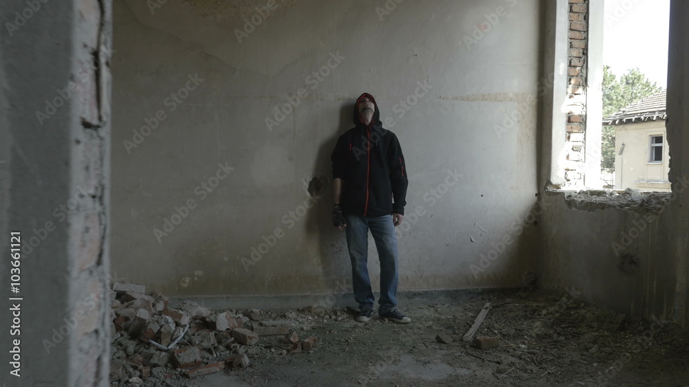 Hooded depressed young man sitting in an abandoned building Hooded depressed young man sitting in an abandoned building