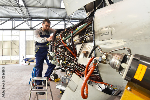 Flugzeugmechaniker repariert die Hydraulik am Triebwerk eines Flugzeuges // Aircraft mechanic repaired the hydraulics on the engine of an airplane