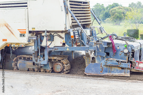 Tracked paver laying fresh aspahlt at road-works   Vehicle tarring a piece of new road.  