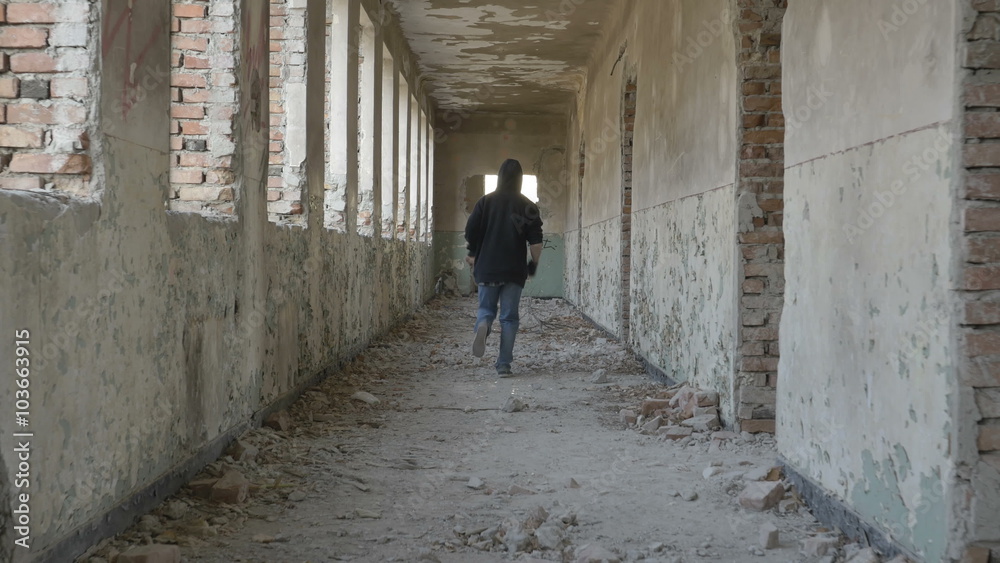 Hooded desperate young man running in an abandoned building Hooded desperate young man running in an abandoned building