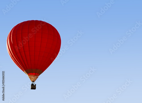 A red hot-air balloon in the sky on a beautiful summer morning.