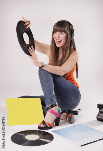 Listen to music
Eine junge Frau sitzt mit offenen Schuhen in denen man ihre Füße sehen kann auf einem Boden und hört über Kopfhörer Musik.
In ihren Händen halte sie eine Schallplatte.