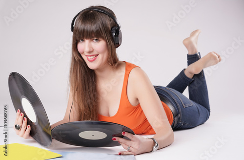 Listen to Music
Eine junge Frau liegt auf dem Boden und hat einen Kopffhörer auf. Sie hört alte Schallpaltten..Sie trägt ein Top mit weitem Ausschnitt und ist barfuß
