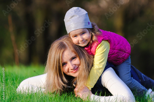 Little girl and her mother hugging outdoors on spring meadow