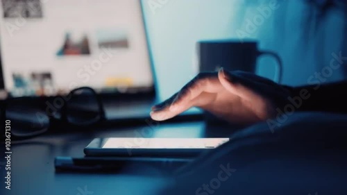 Close up shot of Caucasian female using her mobile phone in dark home office