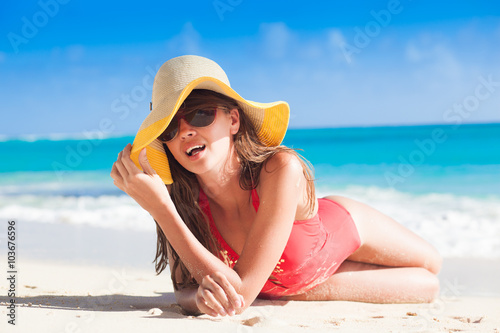 long haired young woman in swimsuit and straw hat on tropical caribbean beach