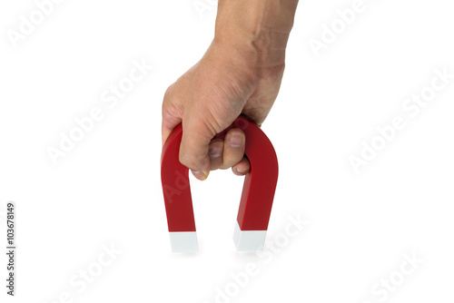 A hand holding a magnet isolated on white to pick up an object
