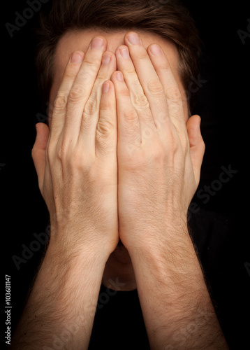 Anxiety concept of depressed man covering face with hands