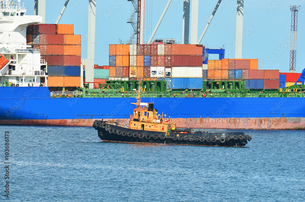 Fototapeta premium Container stack and tugboat under crane bridge