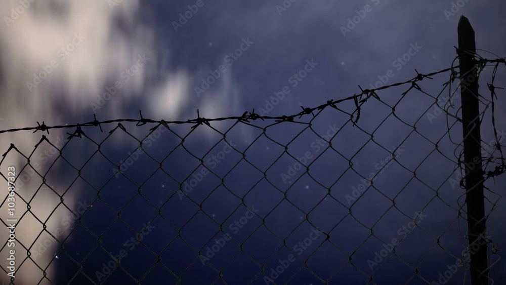 Timelapse of clouds moving fast in the sky on a night full of stars, seen through a fence. Timelapse of clouds moving fast in the sky on a night full of stars, seen through a fence.
