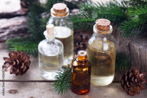 Bottles with fir tree essential aroma oil  on  aged wooden backg
