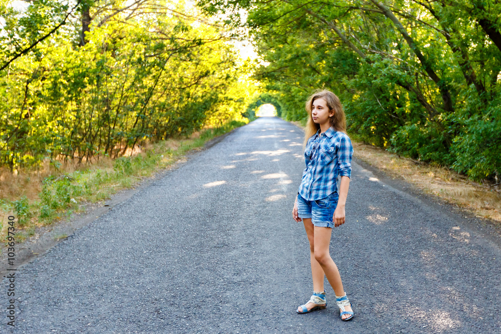 beautiful girl walking on an empty road between green trees beautiful girl walking on an empty road between green trees