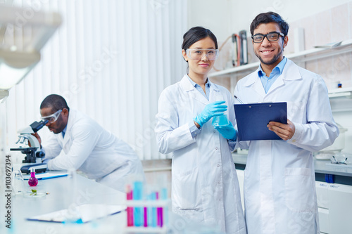 Young scientists in uniform looking at camera in lab