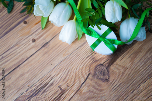 White tulips and a small gift and greenery on wooden board photo