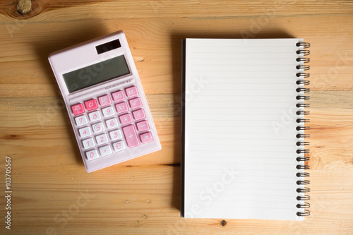 Top view Paper notebook and pink calculator on the wood table