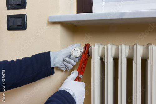 Plumber installing a thermostatic valve on a radiator photo