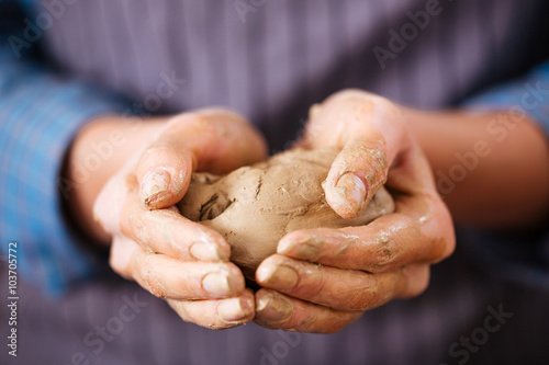Young woman potter hands holding piece of clay