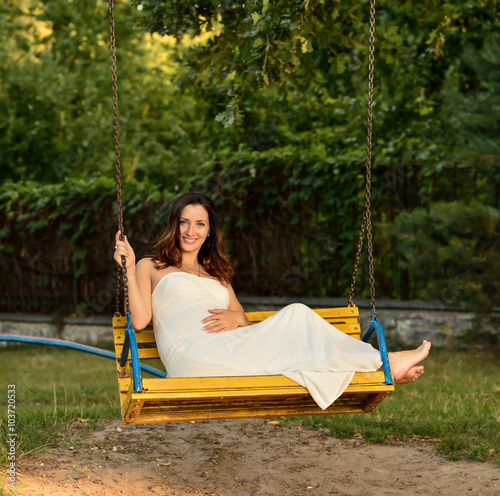 Pregnant woman sitting on a bench warm weather