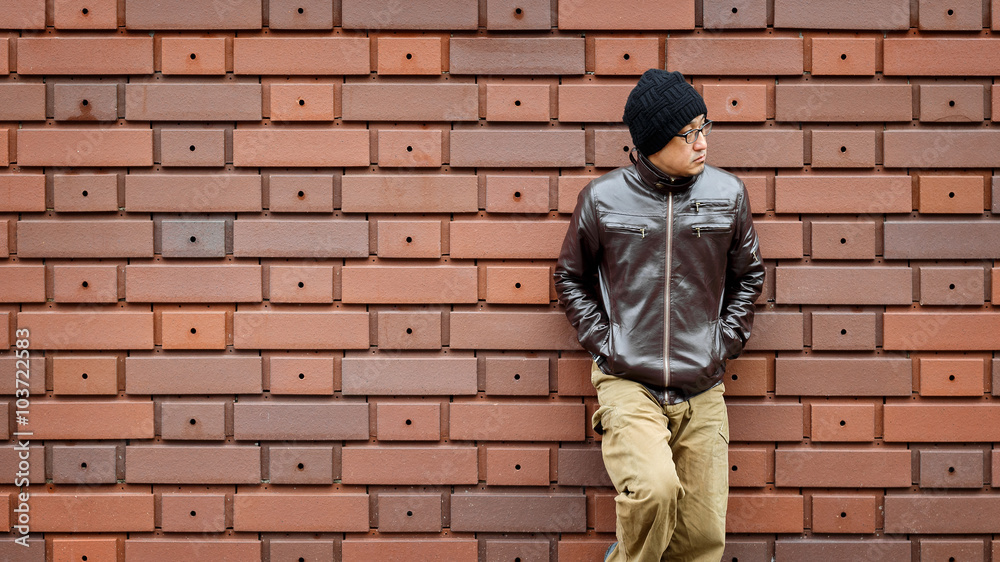 An Asian Man in a Brown Jacket Leans Against the Wall An Asian Man in a Brown Jacket Leans Against the Wall